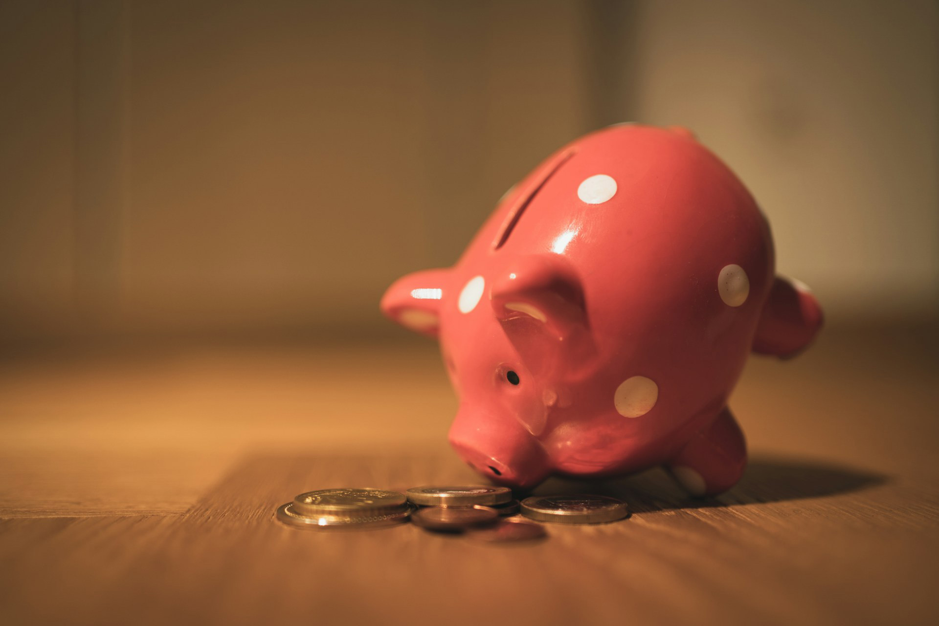Hucha con forma de cerdito rodeada de monedas como símbolo del ahorro financiero en el Día Mundial del Ahorro.